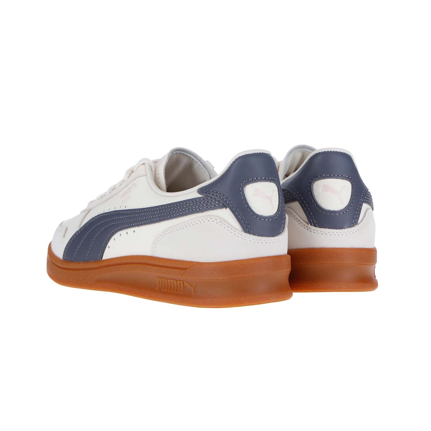 Ein Paar Puma Indoor OG MN Sneakers in mattiertem Elfenbein-Galaktik-Grau mit marineblauen Akzenten und brauner Gummisohle, von hinten und von der Seite betrachtet. Das Puma-Logo erscheint an der Ferse und an der Seite, mit subtilen Lederdetails für zusätzlichen Stil.