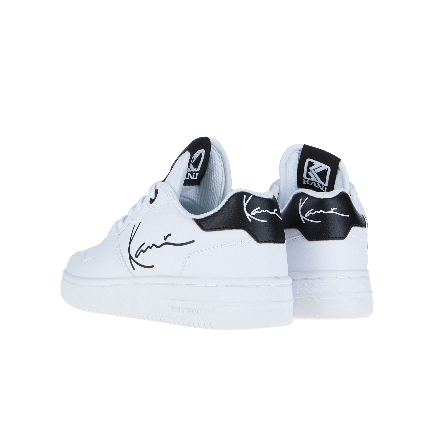 Die Karl Kani Kani 89 Logo GS White/Black WMN sind weiße Low-Top-Sneaker mit schwarzen Akzenten an der Ferse, die aus hochwertigem Textil und Leder gefertigt sind und einen kursiven Schriftzug an der Seite sowie Markenanhänger an Zunge und Ferse aufweisen.