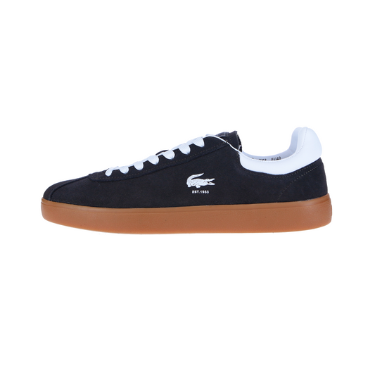Der BASESHOT 224 1 SMA Dark Grey MN von LACOSTE ist ein dunkelgrauer Wildledersneaker mit weißen Schnürsenkeln, einer weißen Ferse und einer braunen Laufsohle. An der Seite befindet sich ein weißes Krokodillogo und der Schriftzug "EST. 1933"-Schriftzug.
