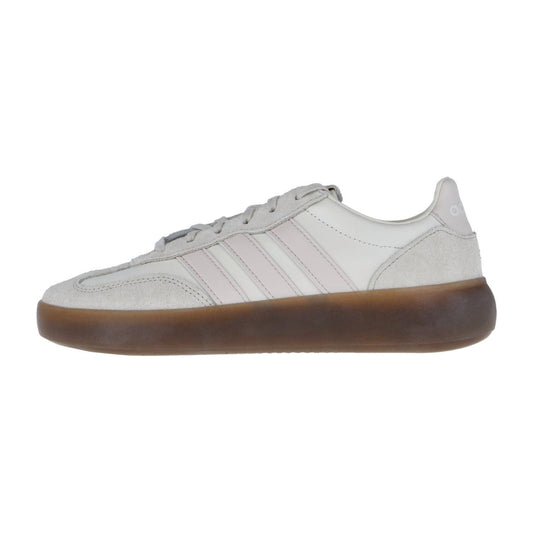 Eine Seitenansicht des Adidas BARREDA DECODE LUX Sneakers in Hellgrau mit weißen Akzenten, blassrosa Streifen, grauen Schnürsenkeln und einer dicken braunen Gummisohle, gefertigt aus hochwertigem Leder für einen gehobenen Look.
