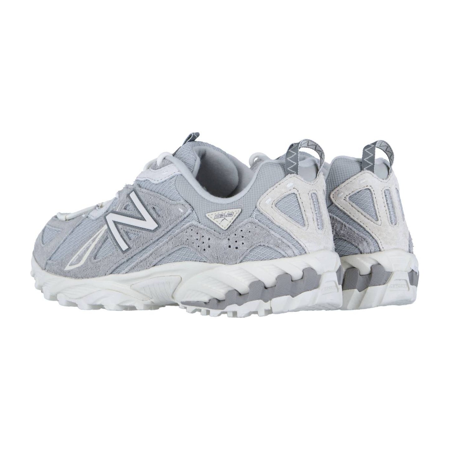Ein Paar hellgraue New Balance ML610TV1 Trail-Sneaker mit weißer Sohle und Akzenten sowie ABZORB-Zwischensohlentechnologie sind von hinten und von der Seite auf weißem Hintergrund zu sehen.