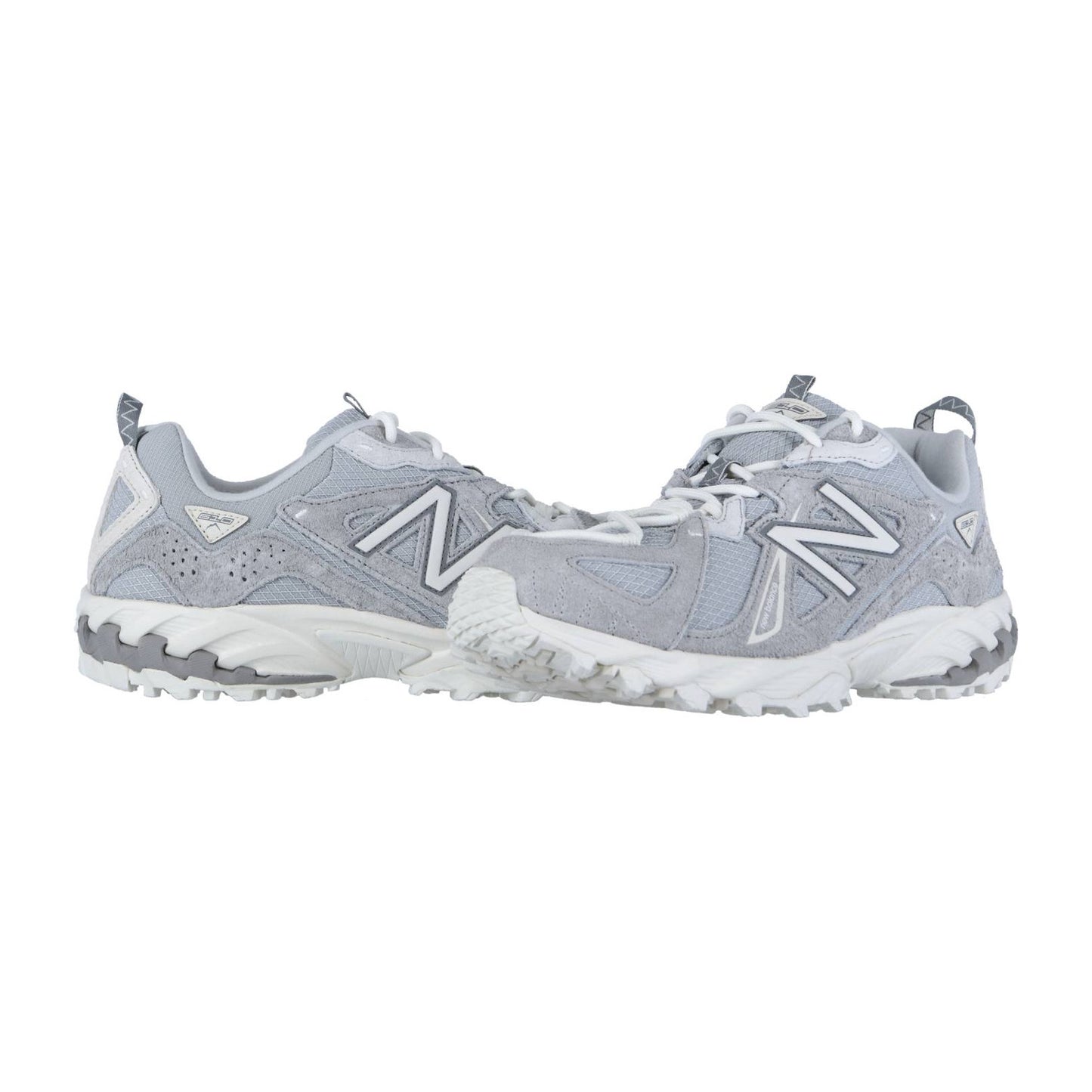 Ein Paar New Balance ML610TV1 Turnschuhe in Hellgrau und Weiß mit klobigen Sohlen, Mesh-Einsätzen, ABZORB-Zwischensohlen und fetten N-Logos sind nebeneinander auf einem weißen Hintergrund abgebildet.