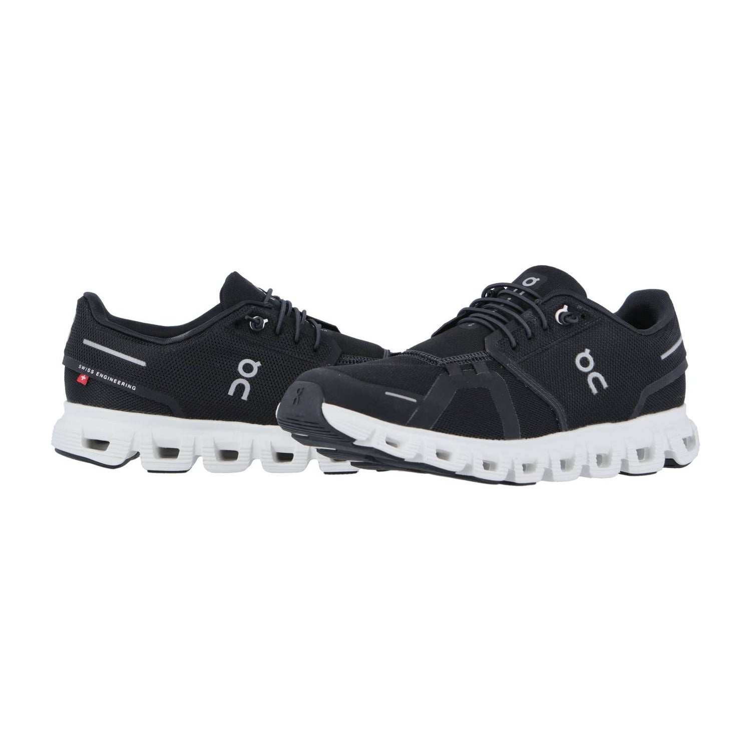 Ein Paar schwarze On CLOUD 6 Laufschuhe mit weißer CloudTec-Sohle und dem On-Logo, das die Schweizer Ingenieurskunst unterstreicht. Ein Schuh steht aufrecht, der andere lehnt sich nach vorne und zeigt das charakteristische segmentierte Sohlendesign.