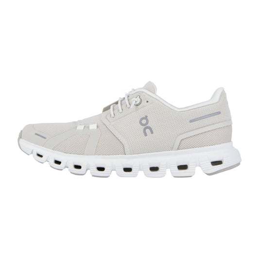 Der CLOUD 6 von On ist ein hellbeiger Sneaker mit weißer Sohle, grauen Akzenten, atmungsaktivem Mesh und dem charakteristischen ON-Logo. Die Sohle ist mit rechteckigen Aussparungen versehen und die CloudTec-Dämpfung sorgt für höchsten Komfort.