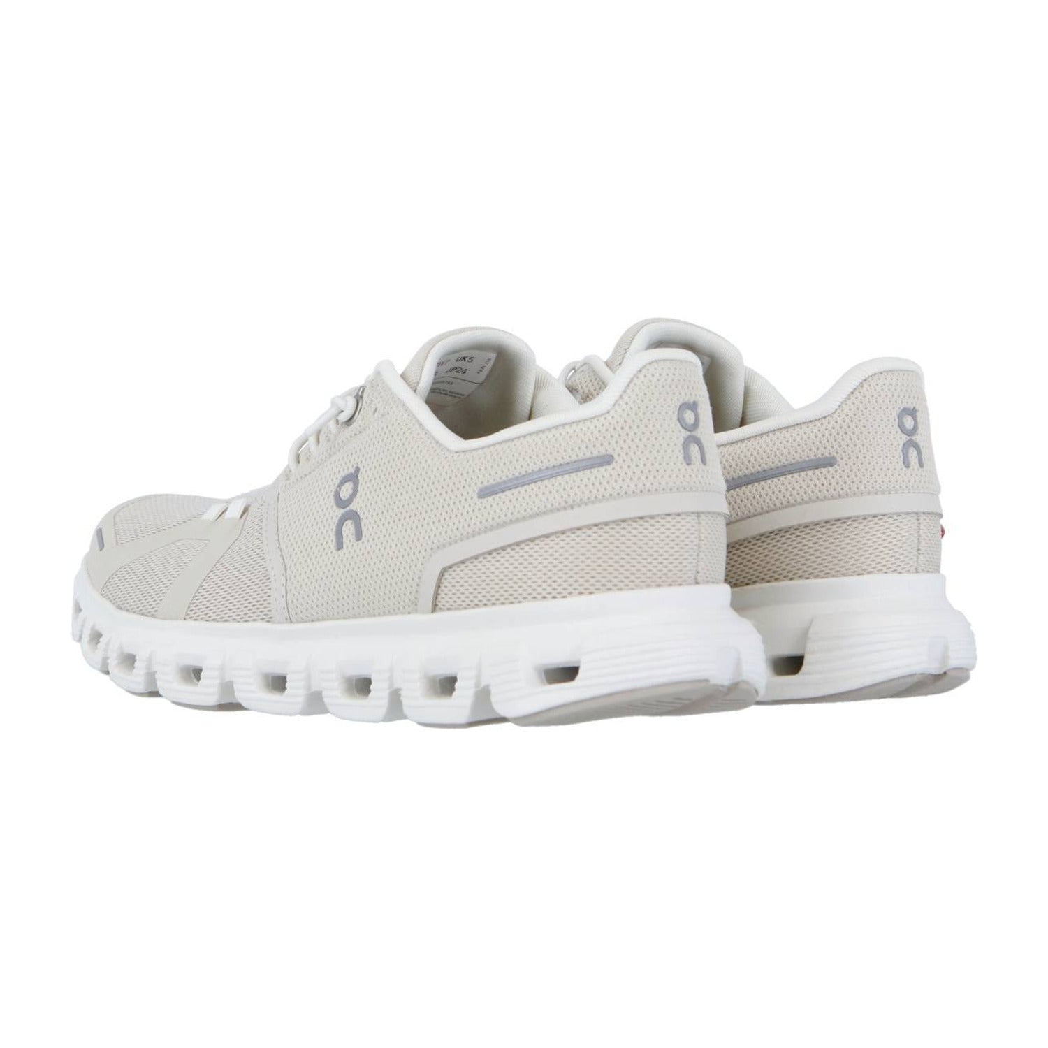 Ein Paar On CLOUD 6 hellbeige Sportschuhe mit weißer, klobiger Sohle und atmungsaktivem Mesh-Obermaterial, von hinten und von der Seite betrachtet. Mit dezentem Branding, minimalistischem Design und CloudTec-Dämpfung für höchsten Komfort.