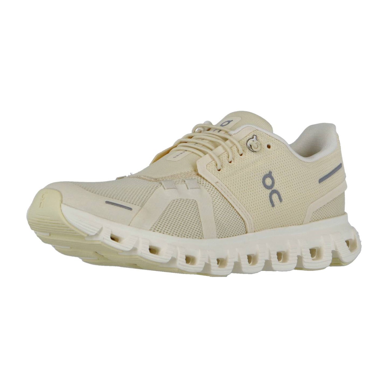 Der CLOUD 6 von On ist ein beiger Sportschuh mit einem Obermaterial aus Mesh, einem Schnürverschluss und der charakteristischen CloudTec-Sohle mit ovalen Aussparungen. Ein dunkelgraues "OC"-Logo an der Seite unterstreicht die Schweizer Ingenieurskunst.