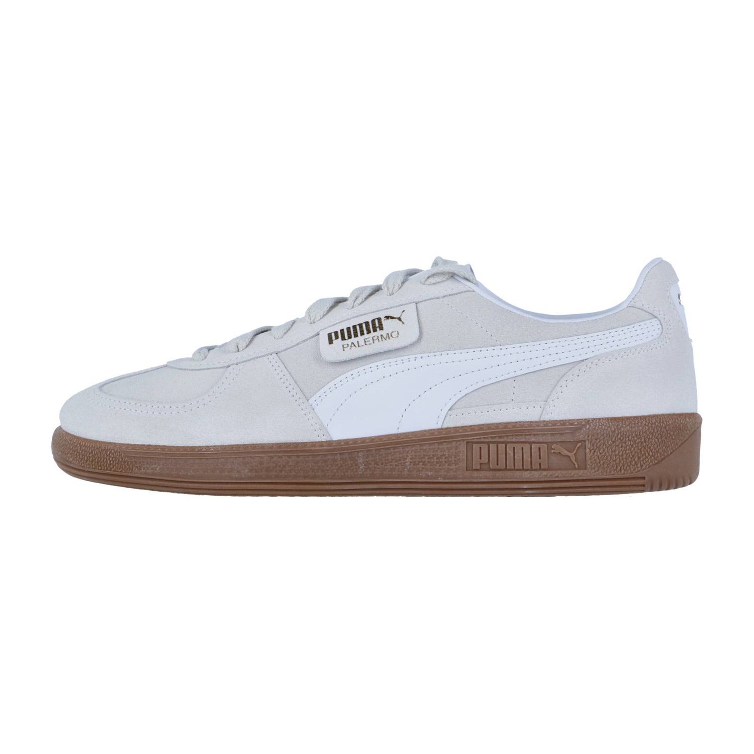 Seitenansicht des Puma Palermo Sneakers in Hellgrau mit weißen Akzenten und einer braunen Gummisohle, mit dem Puma Logo und dem Palermo Branding an den Schnürsenkeln - ein klassischer, von der Terrasse inspirierter Style.