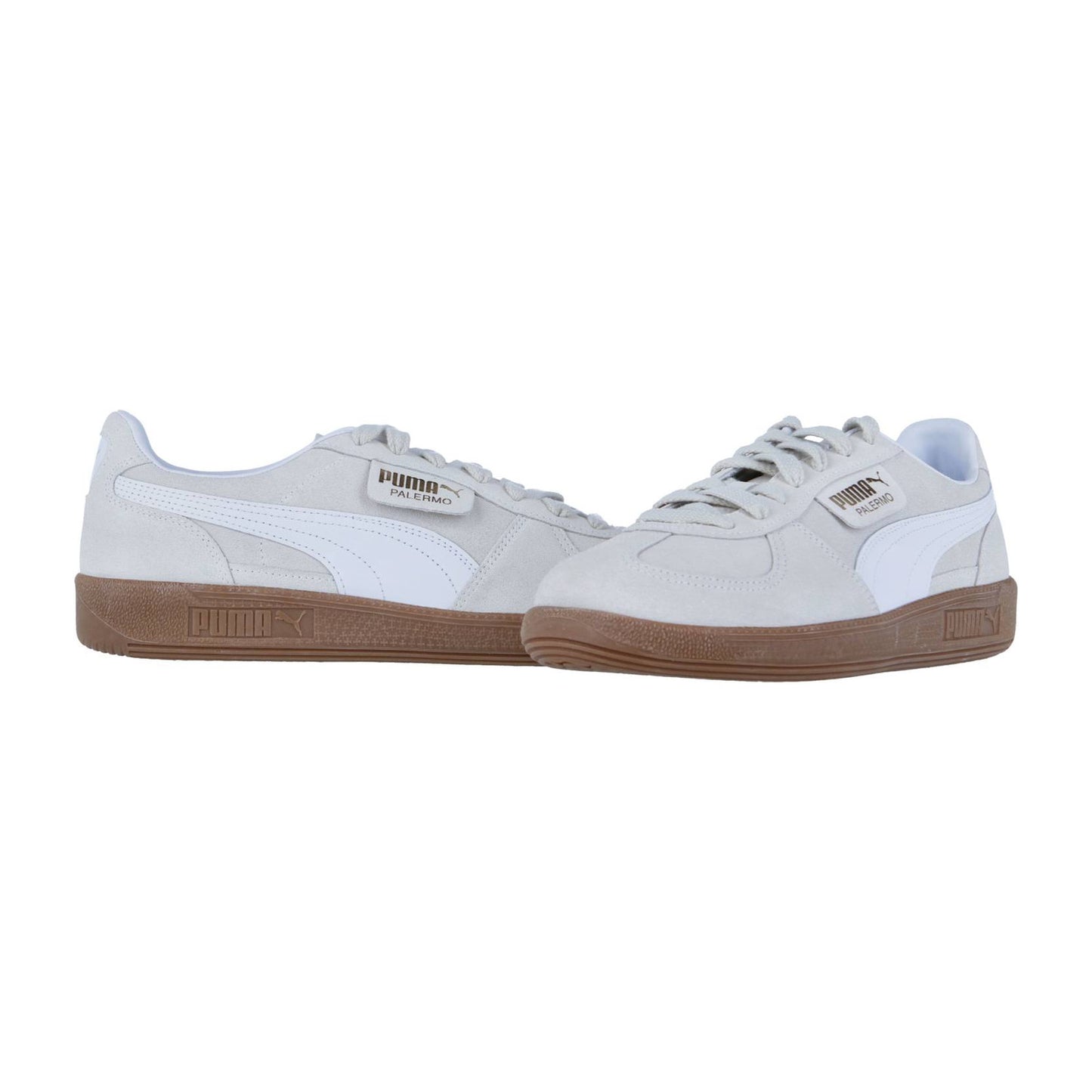 Ein Paar Puma Palermo Sneakers in Hellgrau mit weißen Seitenstreifen und braunen Gummisohlen, nebeneinander auf weißem Hintergrund, unterstreicht den klassischen Terrassenstil und den Retro-Appeal dieses Puma Palermo Modells.