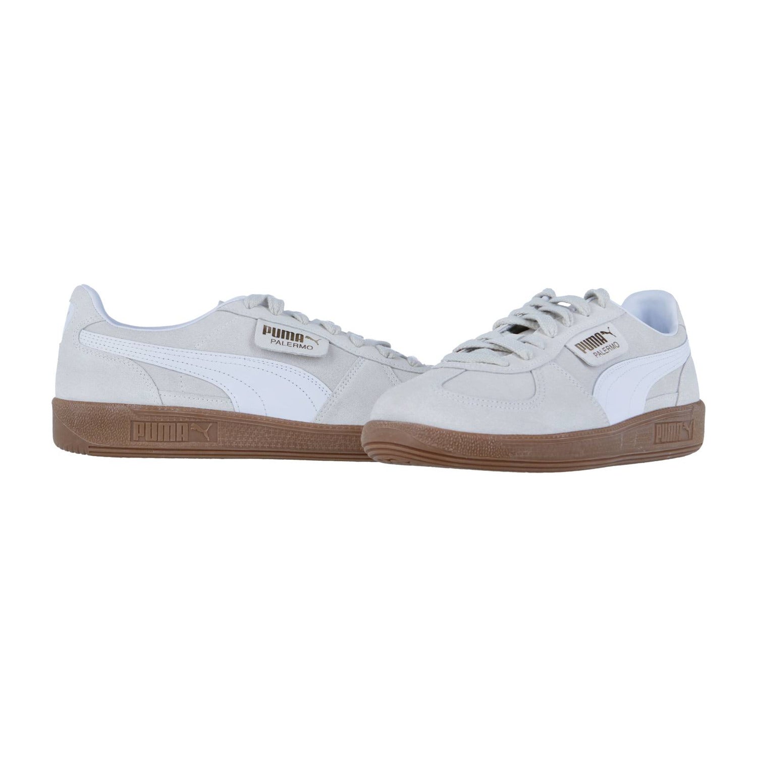Ein Paar Puma Palermo Sneakers in Hellgrau mit weißen Seitenstreifen und braunen Gummisohlen, nebeneinander auf weißem Hintergrund, unterstreicht den klassischen Terrassenstil und den Retro-Appeal dieses Puma Palermo Modells.