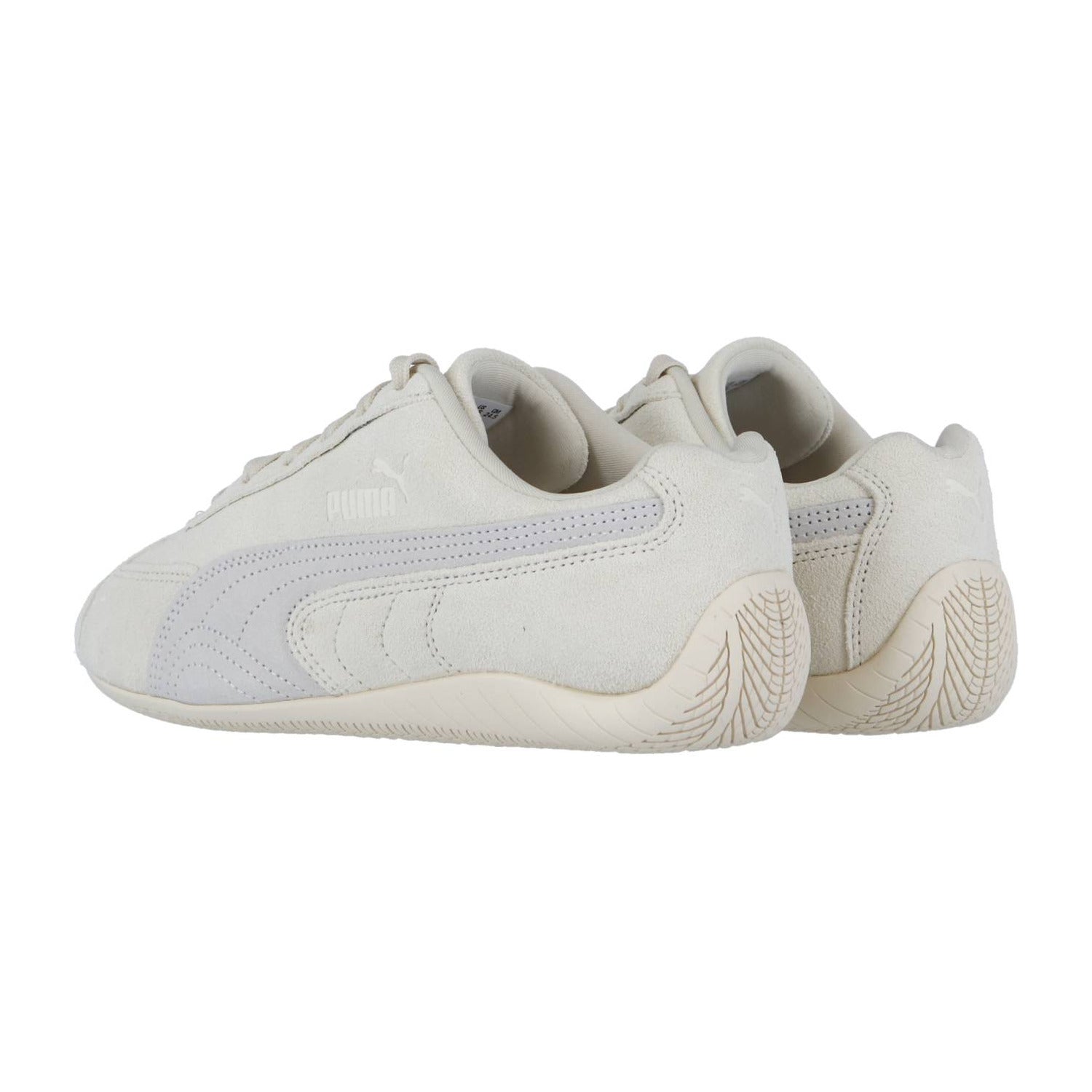Die Puma Speedcat OG Sneakers in Off-White haben ein Wildleder-Finish, ein seitliches Puma-Logo und eine strukturierte beigefarbene Gummisohle, die angewinkelt gezeigt wird, um die Außenseiten und die Rückseite beider Schuhe zu betonen.