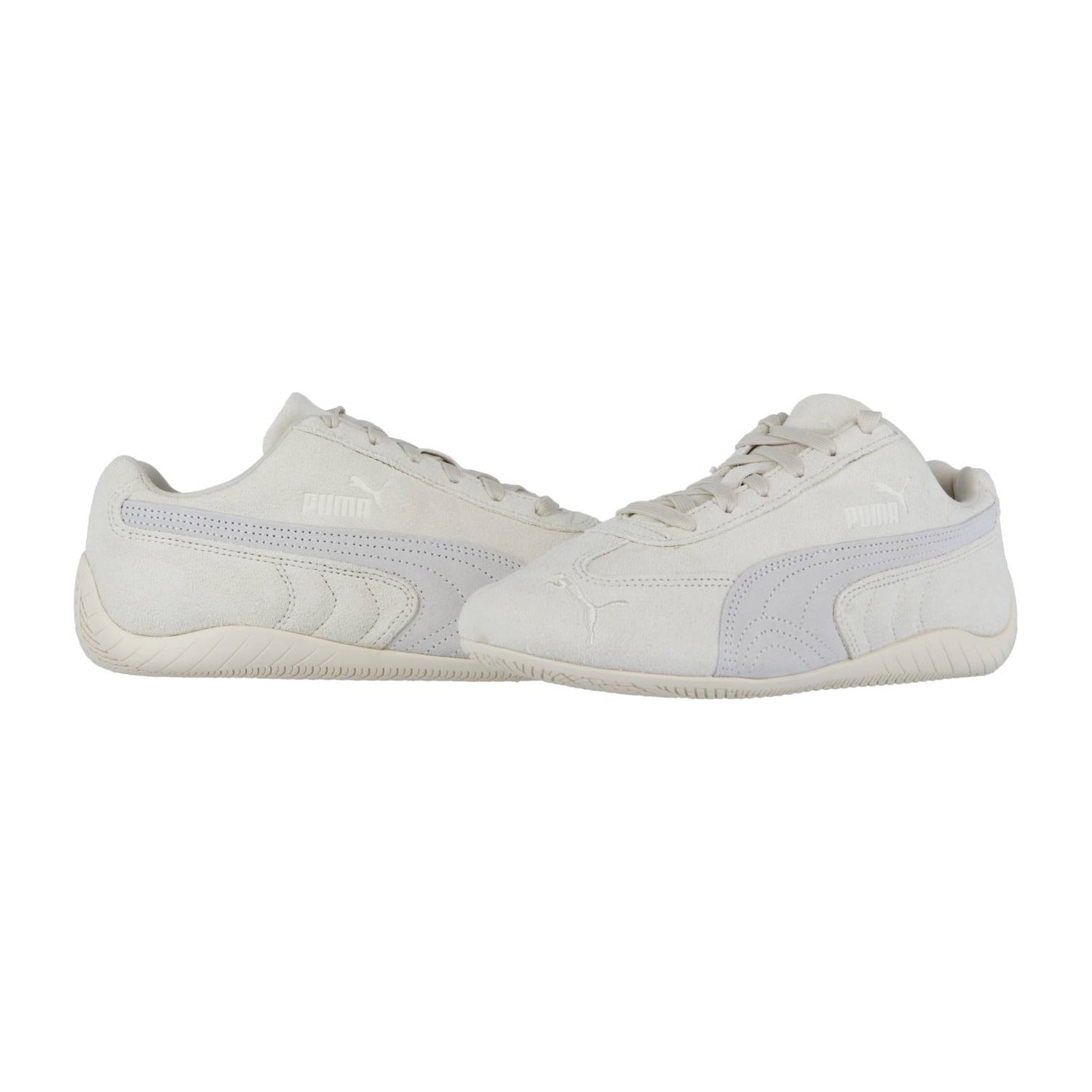 Die Puma Speedcat OG Sneakers zeigen sich in cremefarbenem Wildleder, einem seitlichen Formstrip und dem Puma Logo, inspiriert von klassischen Rennfahrerschuhen. Sie werden auf einem schlichten weißen Hintergrund angezeigt.