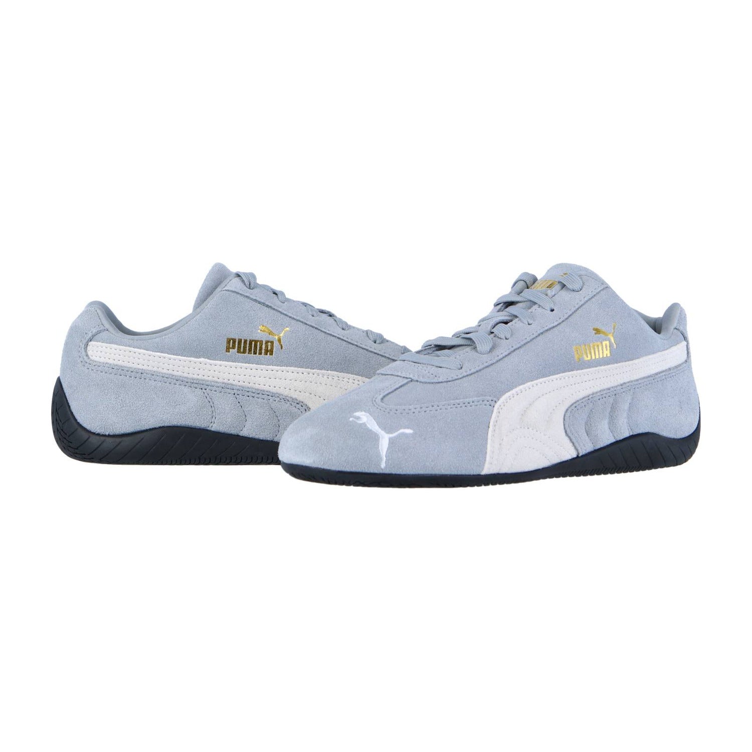 Die Puma Speedcat OG Sneakers haben ein hellgraues Design mit weißen Seitenstreifen, schwarzen Sohlen und goldenen Puma-Logos an den Seiten und auf der Zunge, die sich vor einem weißen Hintergrund präsentieren.