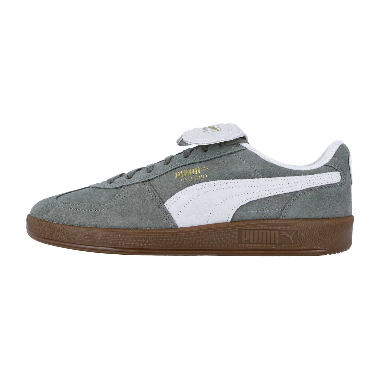 Der Puma Palermo PREMIUM Suede Sneaker hat graues Wildleder, ein weißes Streifenlogo, einen goldenen PUMA KING Schriftzug, graue Schnürsenkel und eine braune Gummisohle in einem retro-inspirierten Seitenprofil.