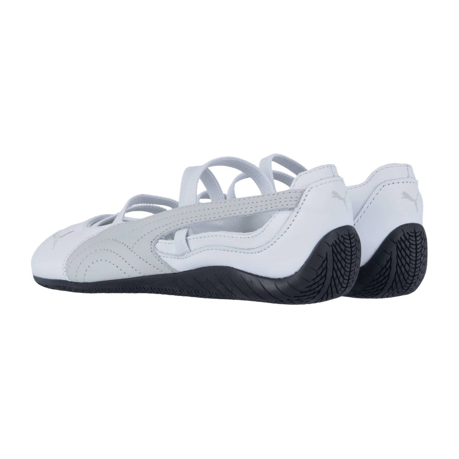 Ein Paar weißer Puma Speedcat Ballet LTH Wns mit grauen Akzenten und dünnen Riemen, mit schwarzer strukturierter Sohle, von hinten und von der Seite betrachtet, zeigt ein elegantes, vom Motorsport inspiriertes Lederdesign.