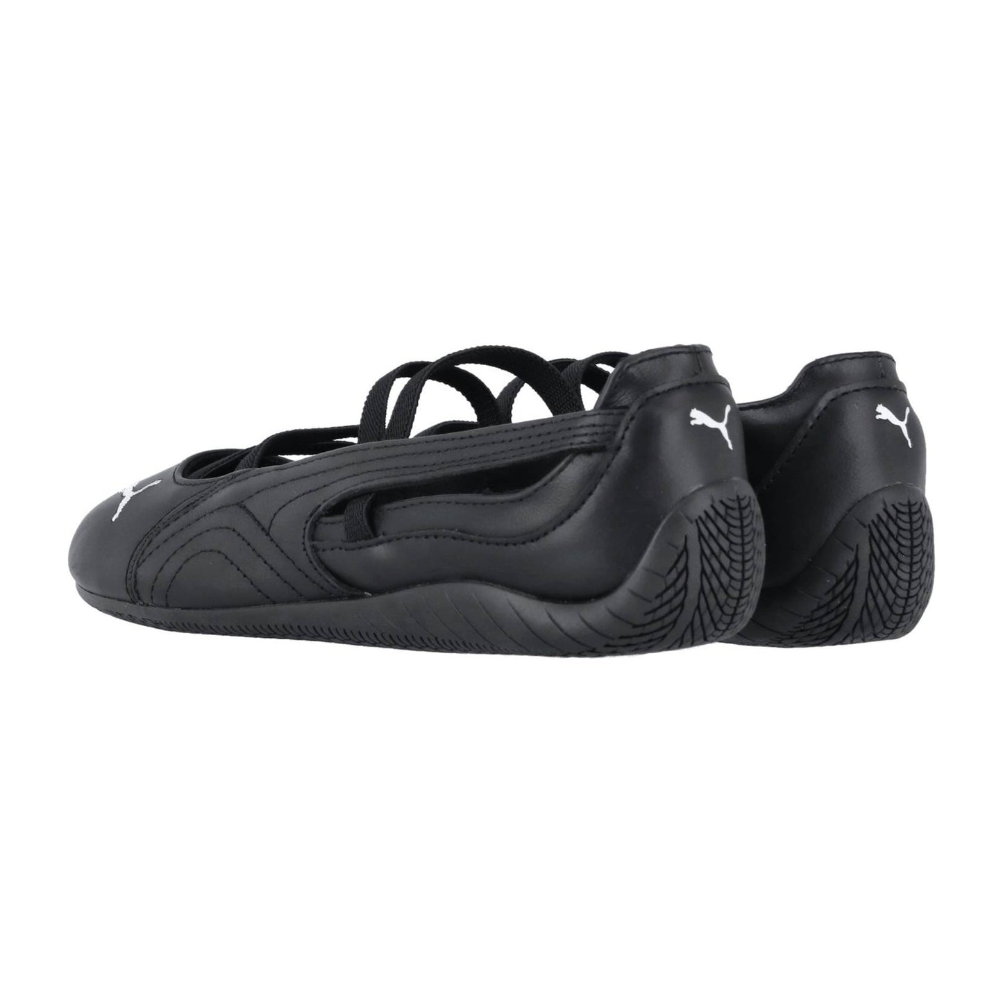 Ein Paar schwarze Puma Speedcat Ballet LTH Wns Turnschuhe mit dünnen, überkreuzten Riemen, flachen Sohlen und weißen Puma-Logos auf den Fersen und an den Seiten, von hinten und leicht zur Seite gesehen.