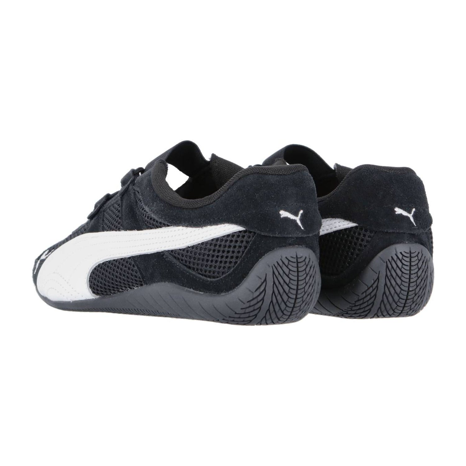 Ein Paar Puma Speedcat Summer Wns Sneakers in Schwarz mit weißen Seitenstreifen und strukturierten Gummisohlen, aus einem Winkel gezeigt, der die Rückseite und die Seite beider Schuhe hervorhebt.