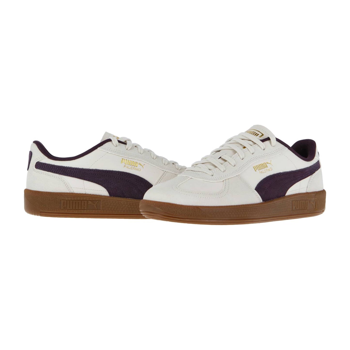 Die Puma Palermo Premium Sneakers haben ein cremefarbenes Obermaterial, dunkelviolette Seitenstreifen, ein goldenes Branding und braune Gummisohlen für den klassischen Fußballterrace-Stil, der vor einem schlichten weißen Hintergrund gezeigt wird.