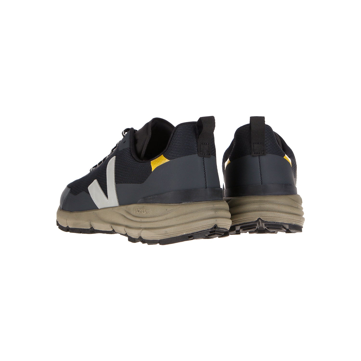 Der Veja Dekkan Alvmesh Black-Oxford Grey-Tonic hat ein schwarzes und graues Obermaterial, eine klobige beigefarbene Sohle aus Amazonas-Gummi, weiße V-Logos an den Seiten und gelbe Akzente an der Ferse, von hinten gesehen in einem leichten Winkel.