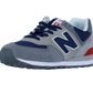 Der New Balance 574 V2 hat graues Wildleder, marineblaue Mesh-Einsätze, dunkelblaue Schnürsenkel, eine weiße Zwischensohle mit ENCAP-Dämpfung, einen roten Fersenakzent und ein charakteristisches N-Logo an der Seite.