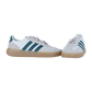 Die Adidas BARREDA DECODE LUX sind luxuriöser Leder-Sneaker in Offwhite mit hellbrauner Sohle, grauen Schnürsenkeln und dunkelgrünen Seitenstreifen, dargestellt auf einem schlichten weißen Hintergrund.