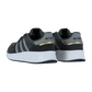 Ein Paar Adidas RUN 84 Turnschuhe in Dunkelgrün und Grau mit schwarzen Streifen, goldenen Fersenakzenten und weißen Sohlen wird von hinten und von der Seite vor einem schlichten weißen Hintergrund gezeigt.