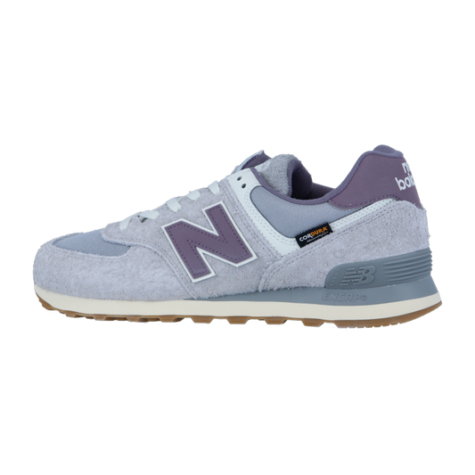 Der New Balance 574 V2 hat ein hellgraues und lilafarbenes Obermaterial aus Wildleder und Mesh, ein auffälliges N-Logo an der Seite und eine beigefarbene Gummisohle mit ENCAP-Dämpfung an der Ferse.