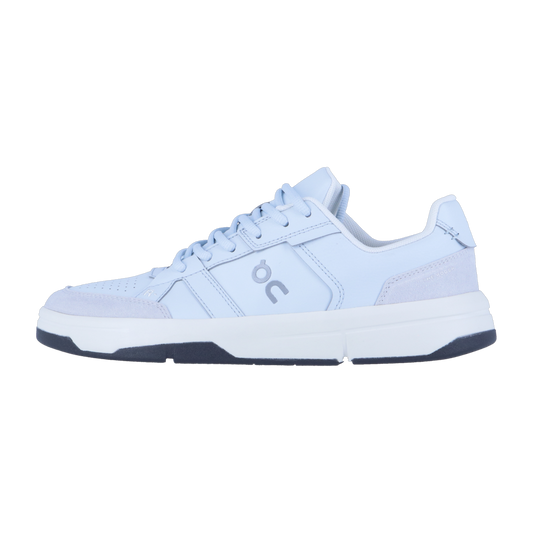 THE ROGER CLUBHOUSE von On ist ein hellblauer Low-Top-Sneaker mit weißer Sohle und dunkelblauer Laufsohle. Er ist aus veganem Leder gefertigt und verfügt über das On-Logo, sichtbare Nähte, Panel-Details und CloudTec Dämpfung für höchsten Komfort.