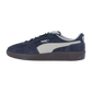 Der Puma Palermo Pop Retro-Sneaker hat ein marineblaues und weißes Wildleder-Obermaterial mit dem Puma-Logo und einer dunklen Sohle, die vor einem schlichten weißen Hintergrund steht.