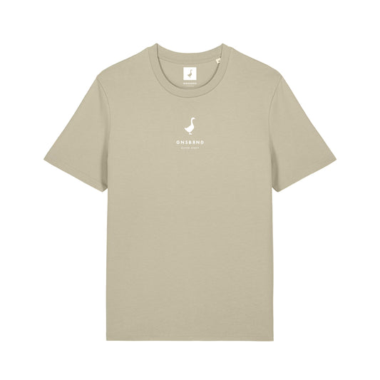 Das Liebesdorf Shirt von GNSBRND ist ein beiges Unisex-T-Shirt aus weicher Bio-Baumwolle mit einem kleinen weißen Enten-Logo und dem ONSBRND ESTD. 2020 auf der Brust gedruckt. Flach auf weißem Hintergrund abgebildet.