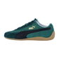 Seitenansicht eines Puma Speedcat Sneakers aus grünem Wildleder mit schwarzem Streifen, goldenem Logo und Gummisohle, mit einem vom Motorsport inspirierten Design auf weißem Hintergrund.