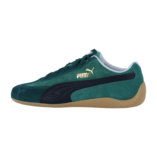 Seitenansicht eines Puma Speedcat Sneakers aus grünem Wildleder mit schwarzem Streifen, goldenem Logo und Gummisohle, mit einem vom Motorsport inspirierten Design auf weißem Hintergrund.