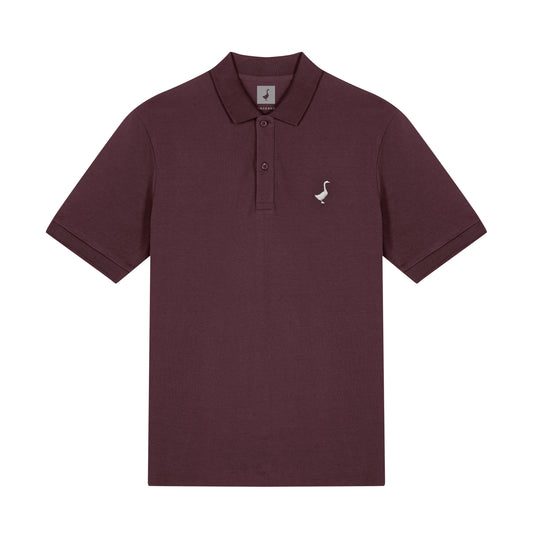 Das GNSBRND Leofels Polo Shirt ist ein kurzärmeliges Polo aus bordeauxfarbener Bio-Baumwolle mit Kragen, drei Knöpfen und einem kleinen weißen Gänse-Logo auf der linken Brust, das auf einem schlichten weißen Hintergrund abgebildet ist.