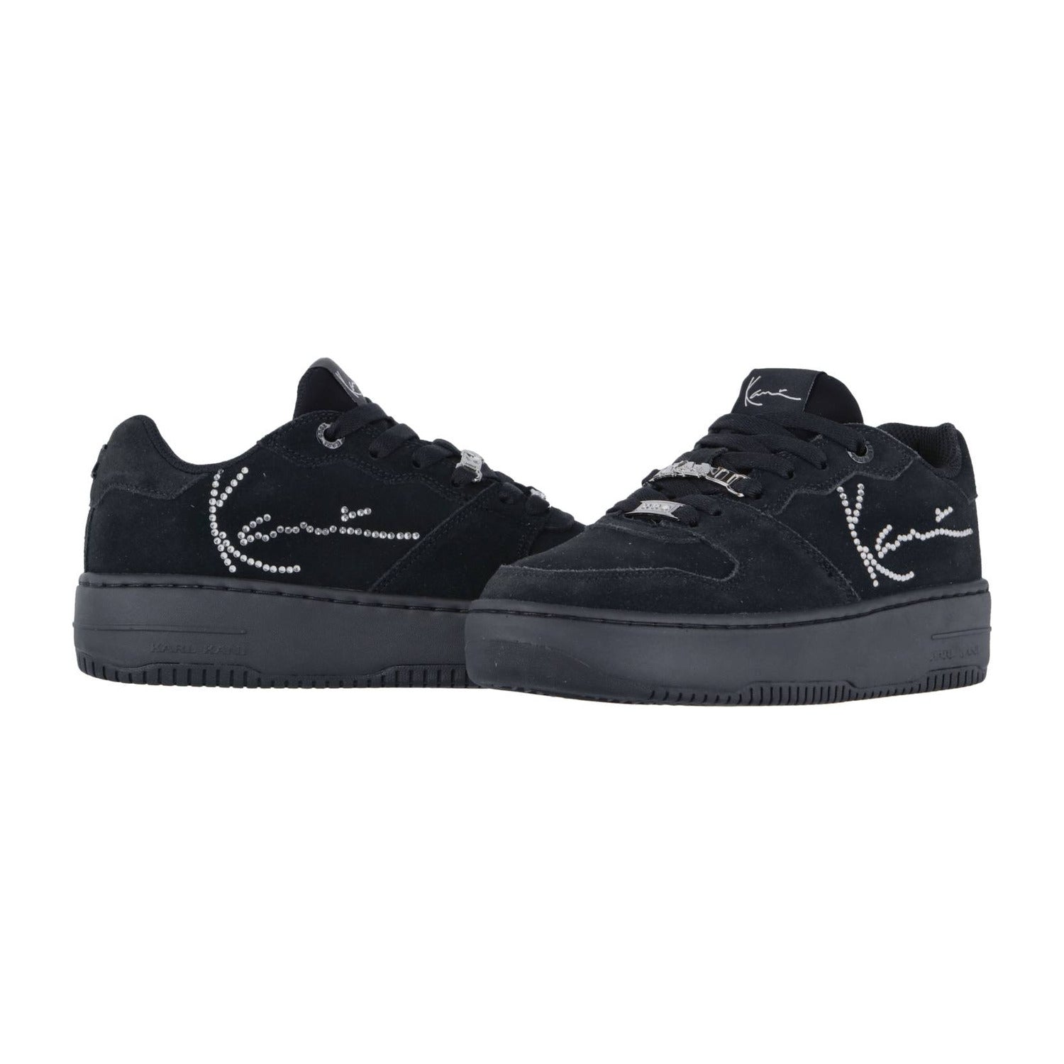Die Low-Top-Sneaker Karl Kani 89 Up Logo Prm Black haben eine dicke Sohle, ein Obermaterial aus Wildleder und ein weißes, mit Strasssteinchen akzentuiertes, kursives Logo an der Seite, das im Streetwear-Stil nebeneinander auf weißem Grund steht.