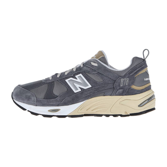 Der New Balance CM878V1 ist ein grauer Sneaker mit weißen und beigen Akzenten, einem weißen N-Logo, einer klobigen beige/weißen Sohle und ABZORB-Dämpfung für Komfort - alles in einem authentischen Retro-Look.