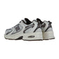 Ein Paar New Balance MR530 Sneakers in Weiß und Grau mit schwarzen und silbernen Akzenten, Obermaterial aus Mesh und Synthetik und klobigen Sohlen, schräg gezeigt.
