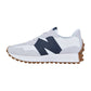 Der New Balance WS327V1 hat ein weißes und hellgraues Design, ein auffälliges dunkelblaues N-Logo an der Seite und eine braune, strukturierte Gummisohle, hier in einem schlanken Seitenprofil.