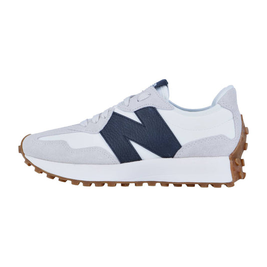 Der New Balance WS327V1 hat ein weißes und hellgraues Design, ein auffälliges dunkelblaues N-Logo an der Seite und eine braune, strukturierte Gummisohle, hier in einem schlanken Seitenprofil.