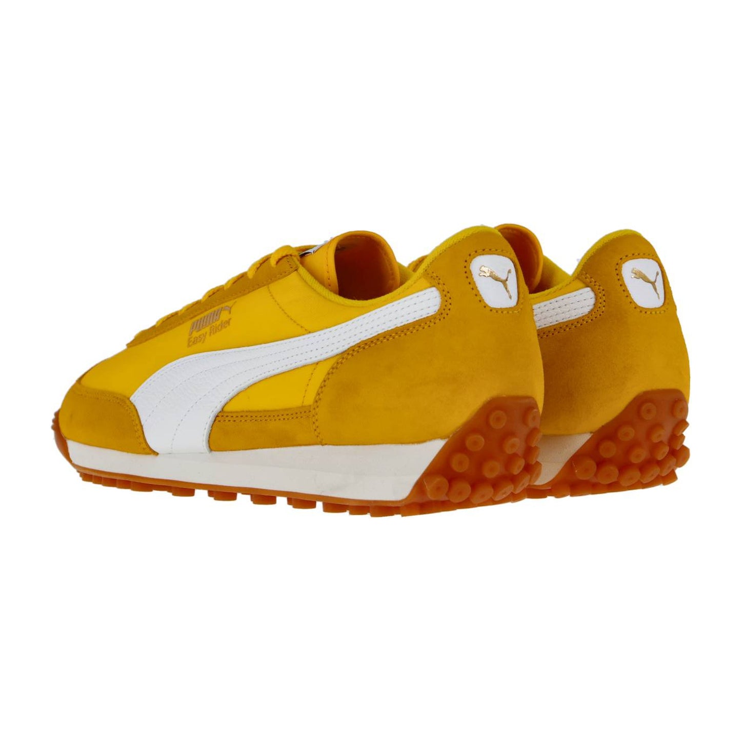 Ein Paar Puma Easy Rider Vintage Turnschuhe in gelb und weiß mit orangefarbenen Sohlen, die von hinten und von der Seite auf einem weißen Hintergrund dargestellt sind. Das Puma-Logo erscheint an der Ferse und an der Seite jedes Schuhs.