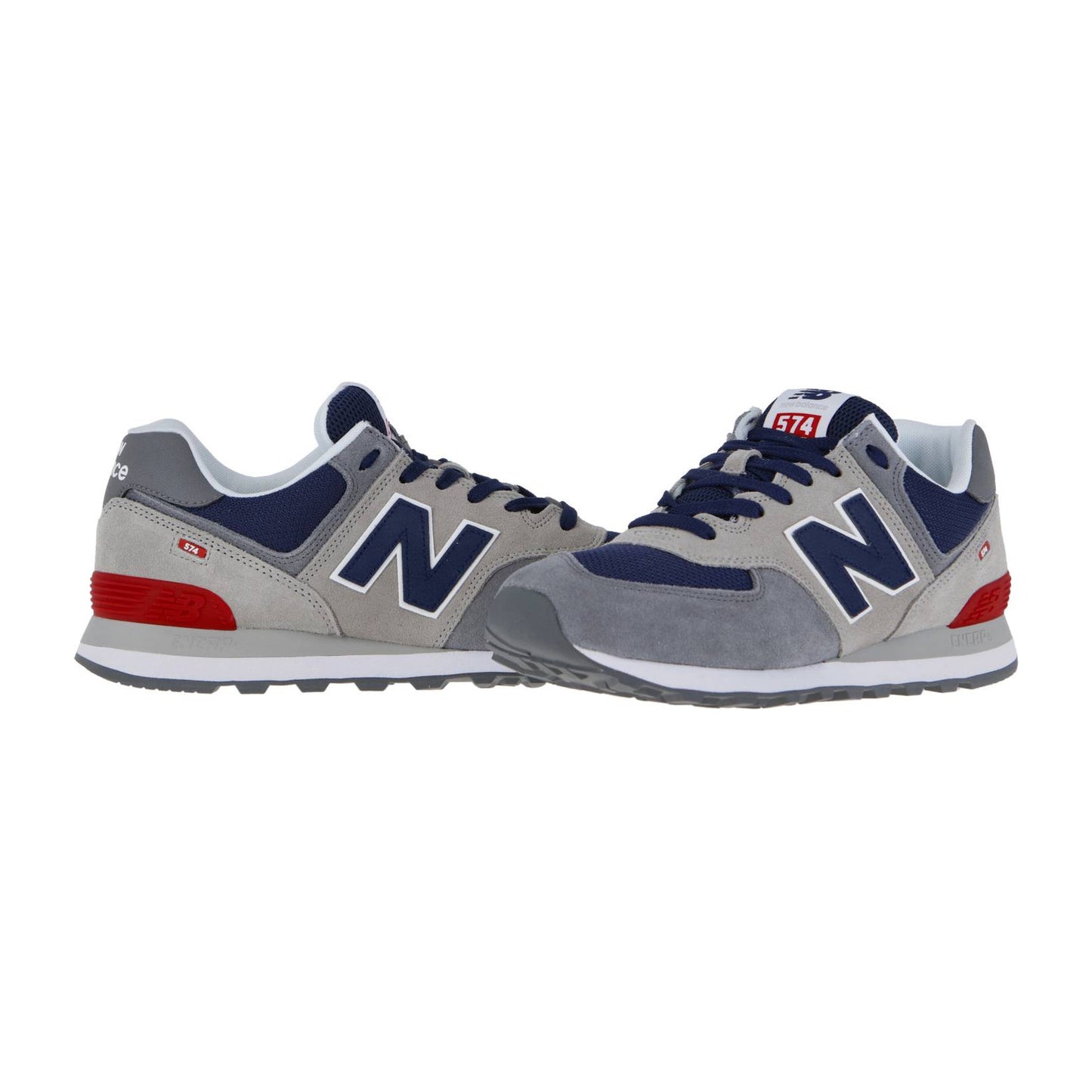 Ein Paar New Balance 574 V2 Sneakers in Grau, Marineblau und Weiß mit roten Akzenten. Ein Schuh steht aufrecht, der andere liegt auf der Seite und zeigt das "N"-Logo, die profilierte Gummisohle und die ENCAP-Dämpfung für Komfort.