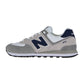 Ein grauer und weißer New Balance 574 V2 Sneaker mit einem navyfarbenen N-Logo, weißen Schnürsenkeln, Wildleder- und Mesh-Akzenten und einer dunkelgrauen ENCAP-Dämpfungssohle. Abgebildet im Seitenprofil vor einem weißen Hintergrund.