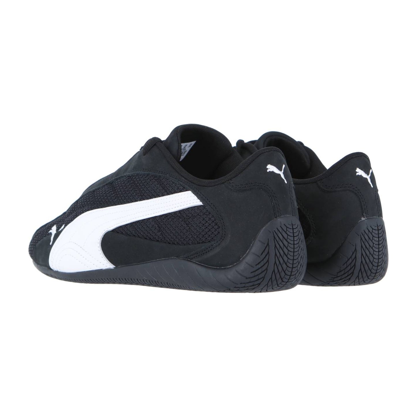 Die Puma Speedcat Plus Sneakers in Schwarz mit weißem Puma-Logo und dynamischem Seitendesign sind so angewinkelt, dass sowohl die Außenseite als auch die Rückseite vor einem weißen Hintergrund zu sehen sind.