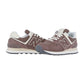 Ein Paar New Balance WL574V2 Turnschuhe in Braun und Beige mit weißer Zwischensohle und grauer Laufsohle sind nebeneinander auf einem weißen Hintergrund platziert.