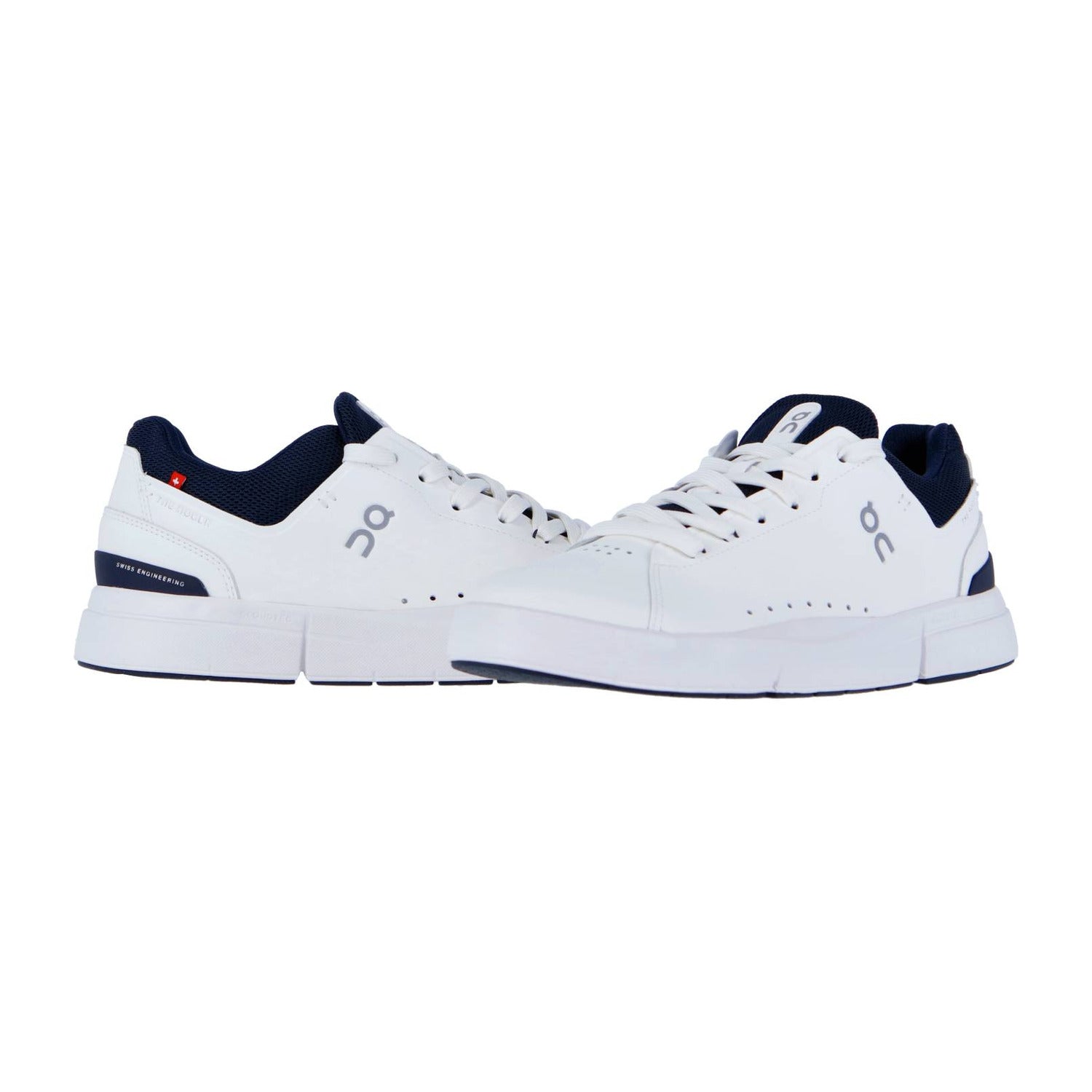 THE ROGER ADVANTAGE von On: weiße Sportschuhe mit marineblauen Akzenten und dem On-Logo, inspiriert von Roger Federer und der Schweizer Performance-Technologie. Abgebildet auf weißem Hintergrund, ein Schuh zeigt nach vorne, der andere schräg.
