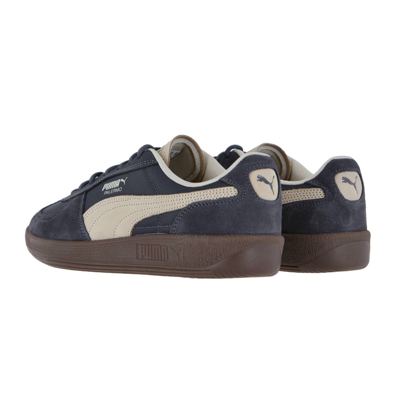 Ein Paar Puma Palermo Pop Sneakers in Marineblau mit beigen Seitenstreifen und dunkelbrauner Sohle, schräg gezeigt, um das Äußere und die Rückseite zu zeigen - ideal für Liebhaber der Retro-Sneaker Terrace-Kollektion.